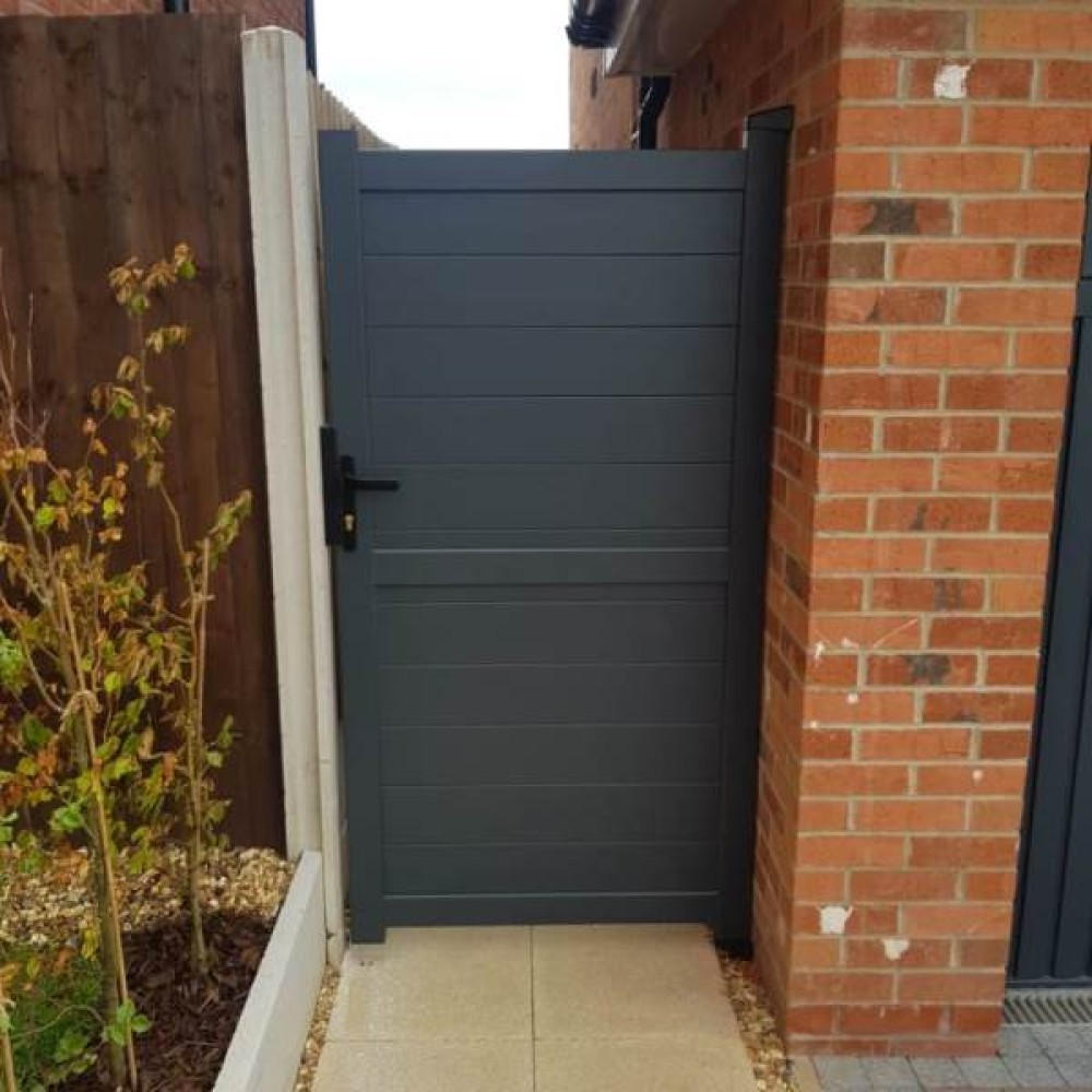 Grey horizontal board aluminium side gate beside a brick wall