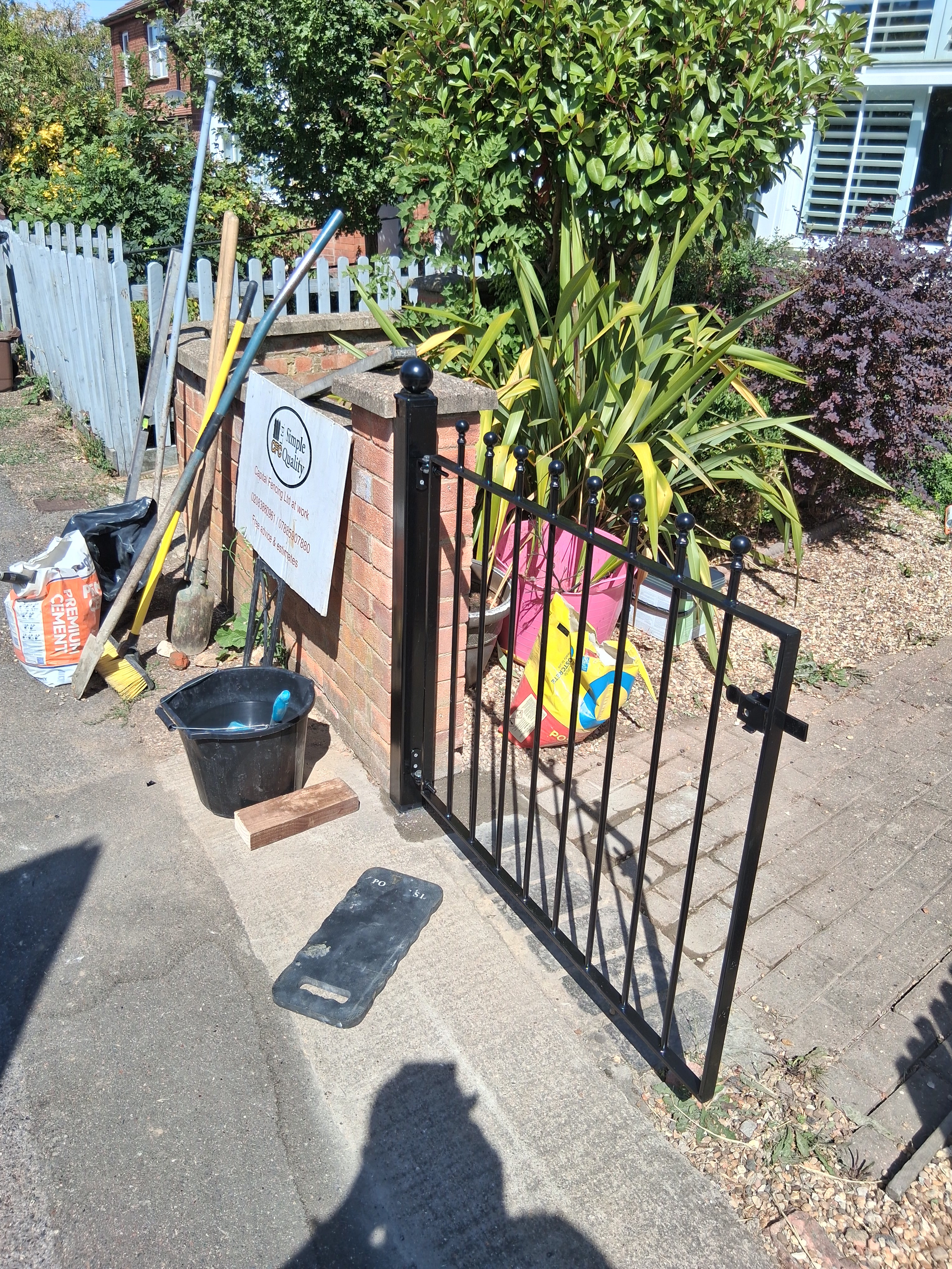 Welded black ball-top gate leaf standing on site before being hung on its posts